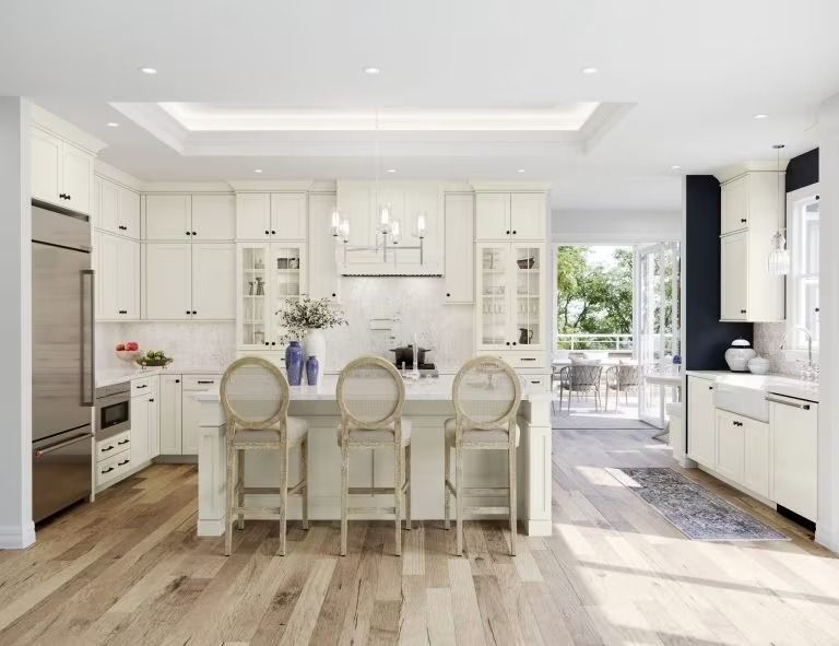 Bright white modern kitchen with island, three chairs, wood floors, and large windows overlooking greenery