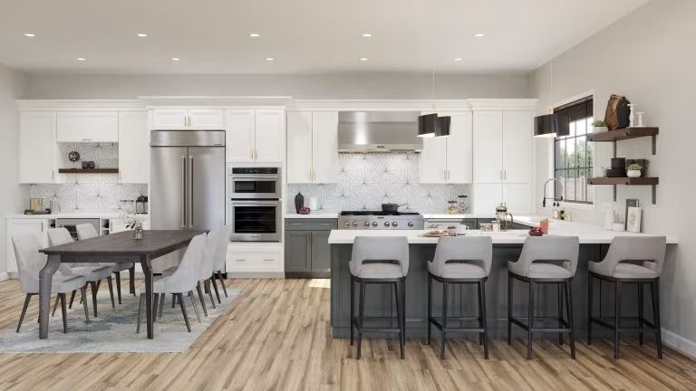 Bright modern kitchen with white cabinets, island seating, dining table, and stainless steel appliances