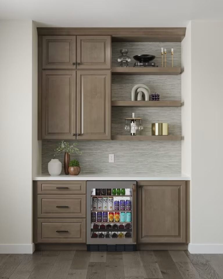 Built-in bar cabinet with wood shelves, drawers, and a small drink fridge against a white wall