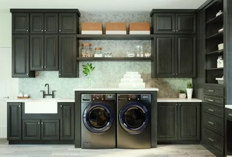 Modern laundry room with black cabinets, front-loading washer and dryer, open shelves, and light tile walls