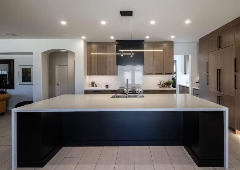 Modern kitchen with large island, wood cabinets, stainless range hood, and tiled floor