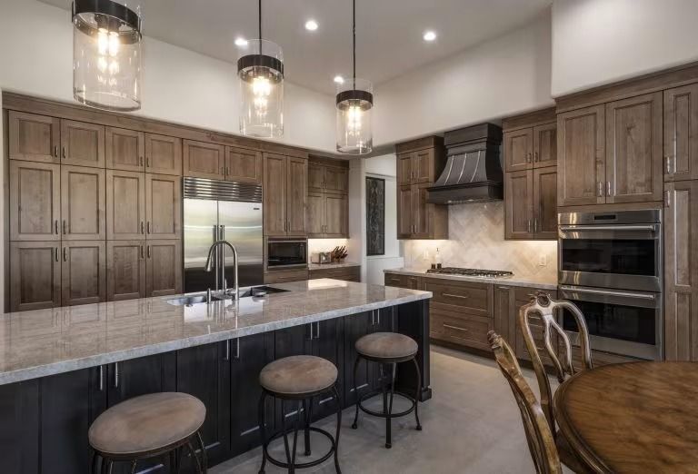 Modern kitchen with wood cabinets, large island, pendant lights, and built-in ovens