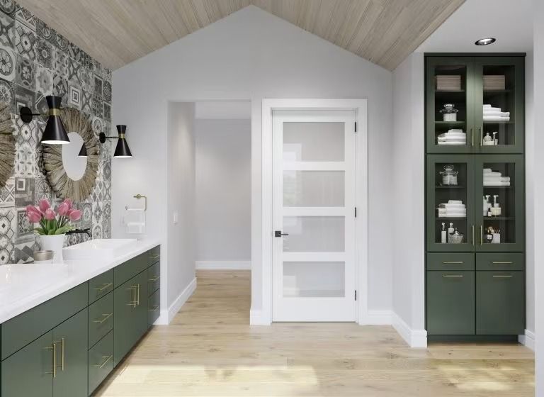 Modern bathroom with green cabinets, white door, marble countertop, and vaulted wood ceiling