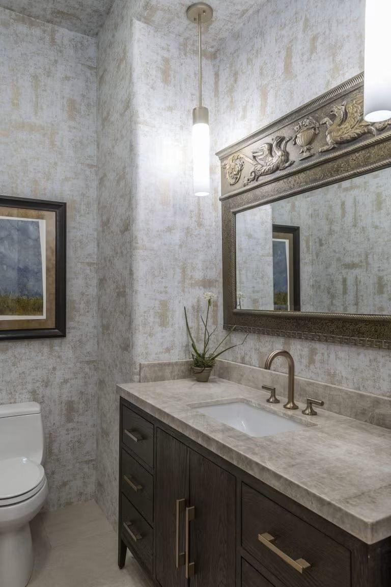 Small elegant bathroom vanity with marble countertop, mirror, wall sconce, and dark wood cabinets