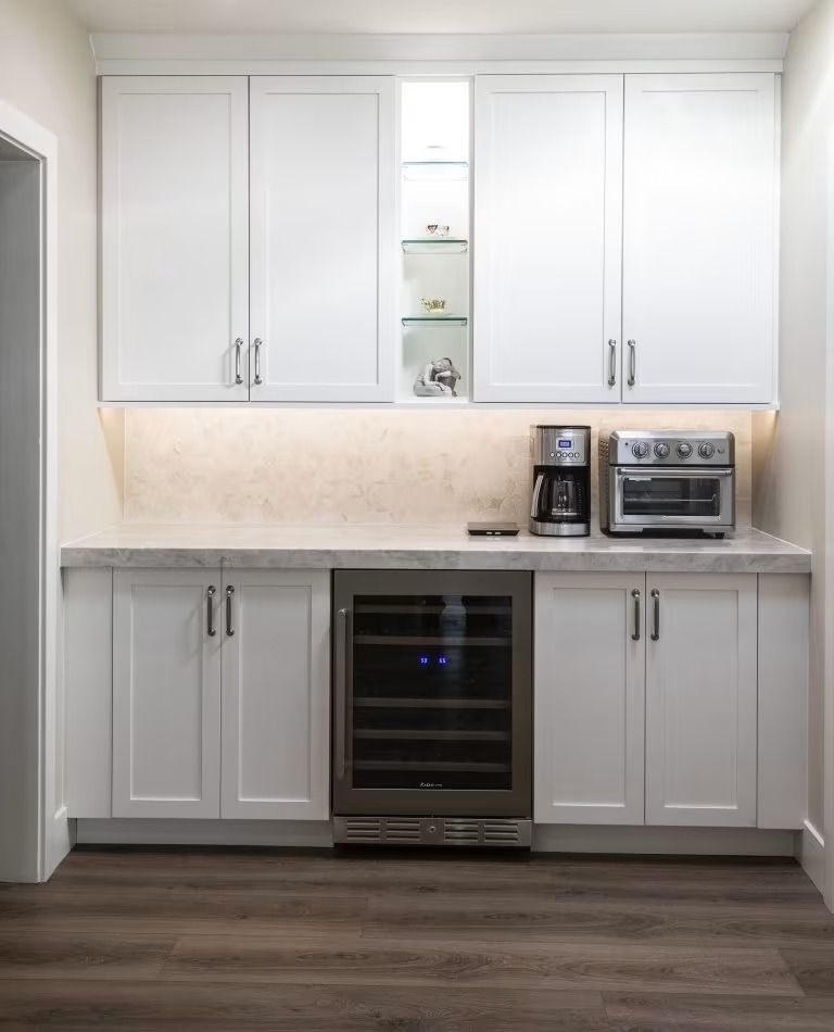 Modern white kitchen cabinets with countertop, coffee maker, toaster oven, and built-in wine cooler