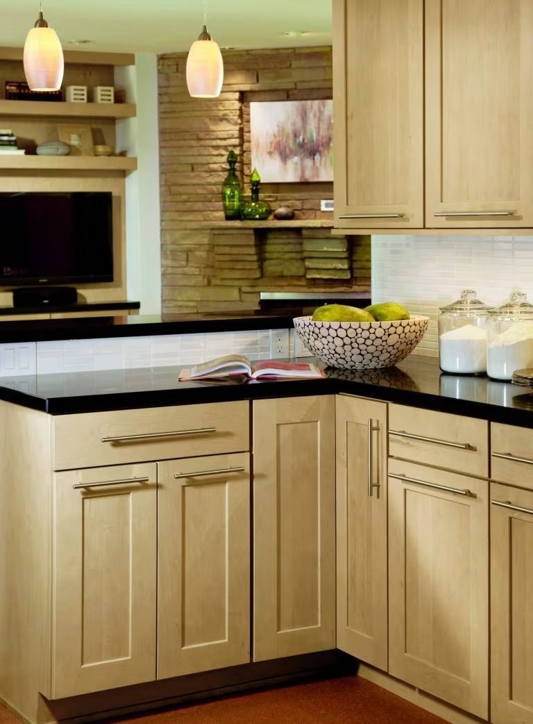 Modern kitchen with light wood cabinets, black countertop, and pendant lights