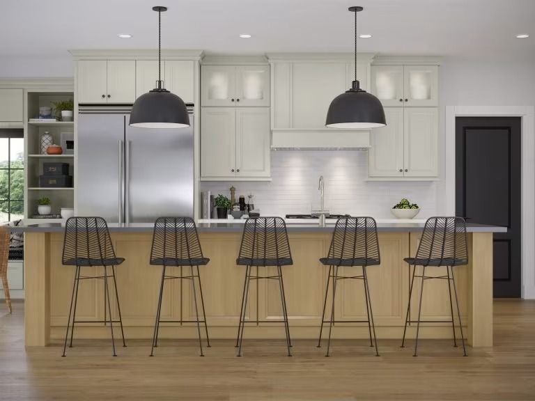 Modern kitchen with island, black barstools, stainless steel fridge, and two pendant lights