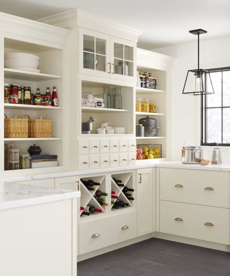 Bright white kitchen pantry with open shelves, drawers, and bottles of wine and food items