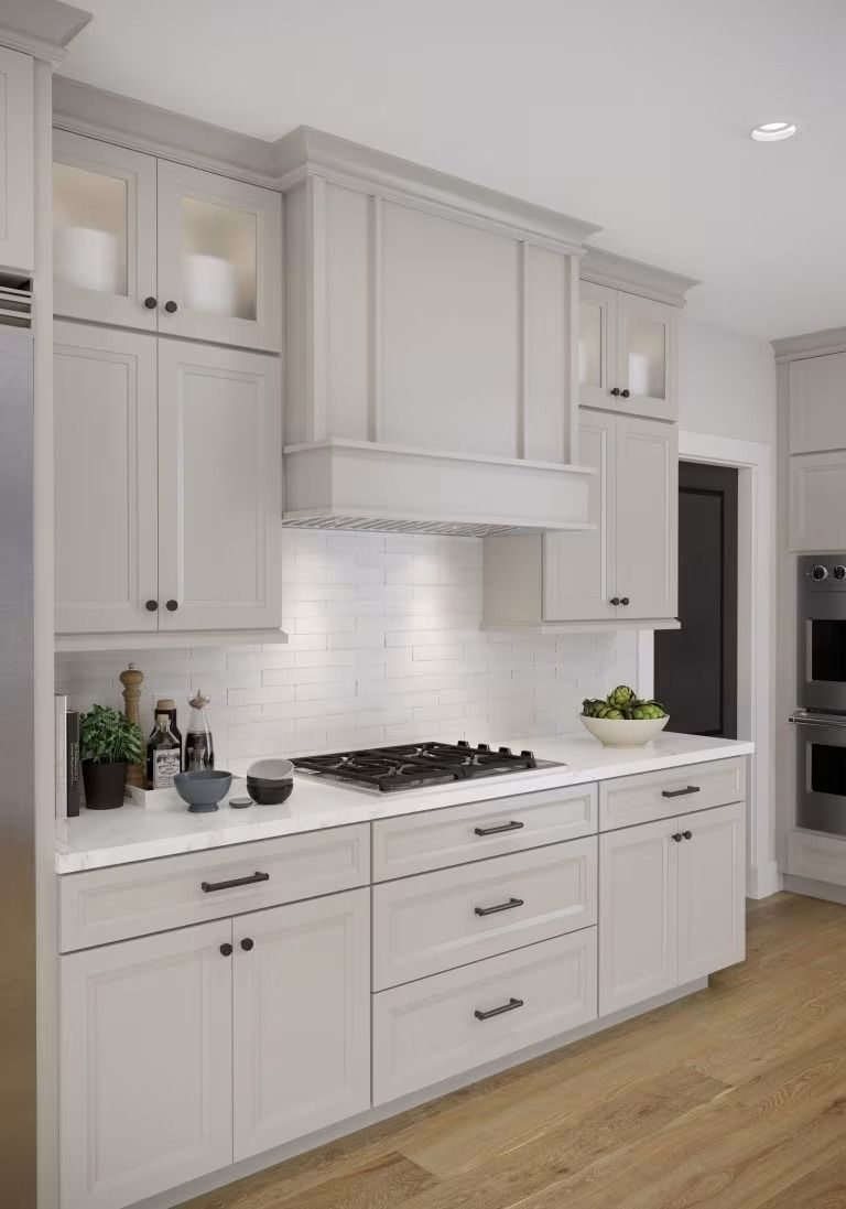Bright white modern kitchen with cabinets, stainless range, tile backsplash, and wood floors.