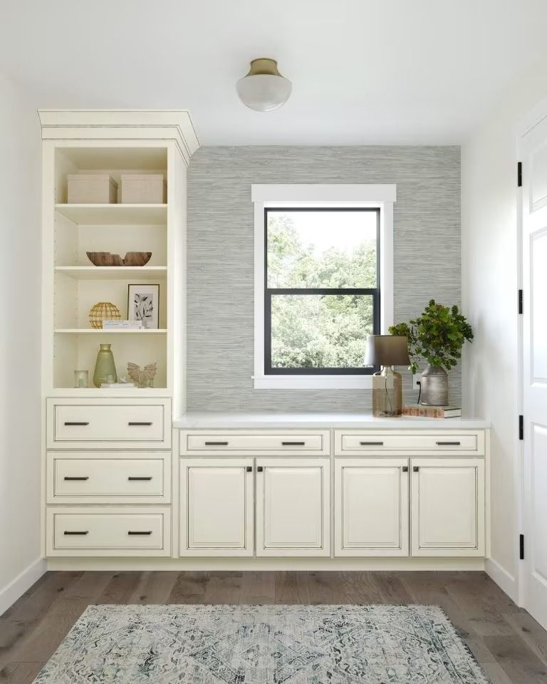 Bright built-in white cabinets and shelving under a window in a clean, modern room with a rug.