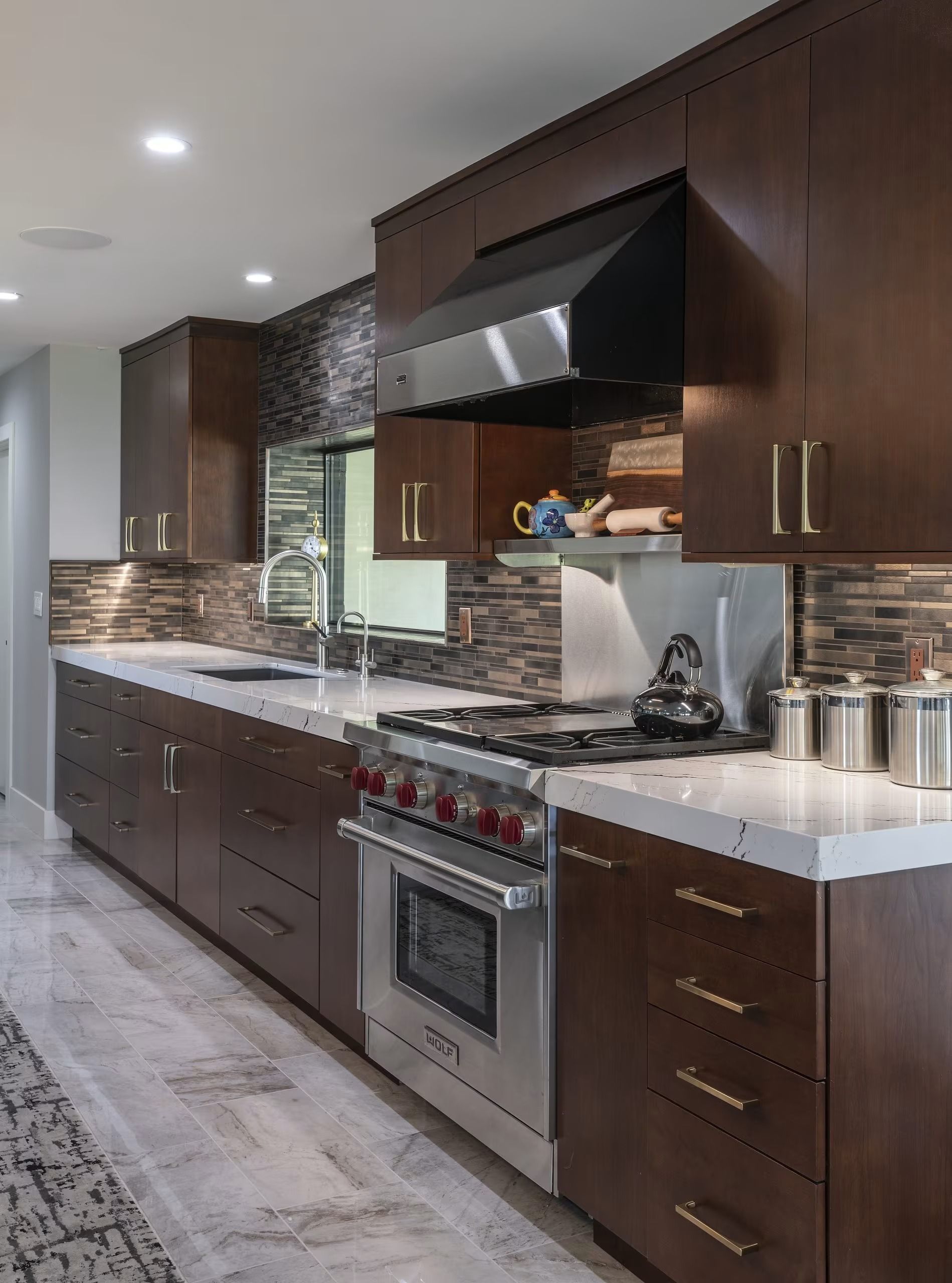 Modern kitchen with dark wood cabinets, stainless steel appliances, and white countertops