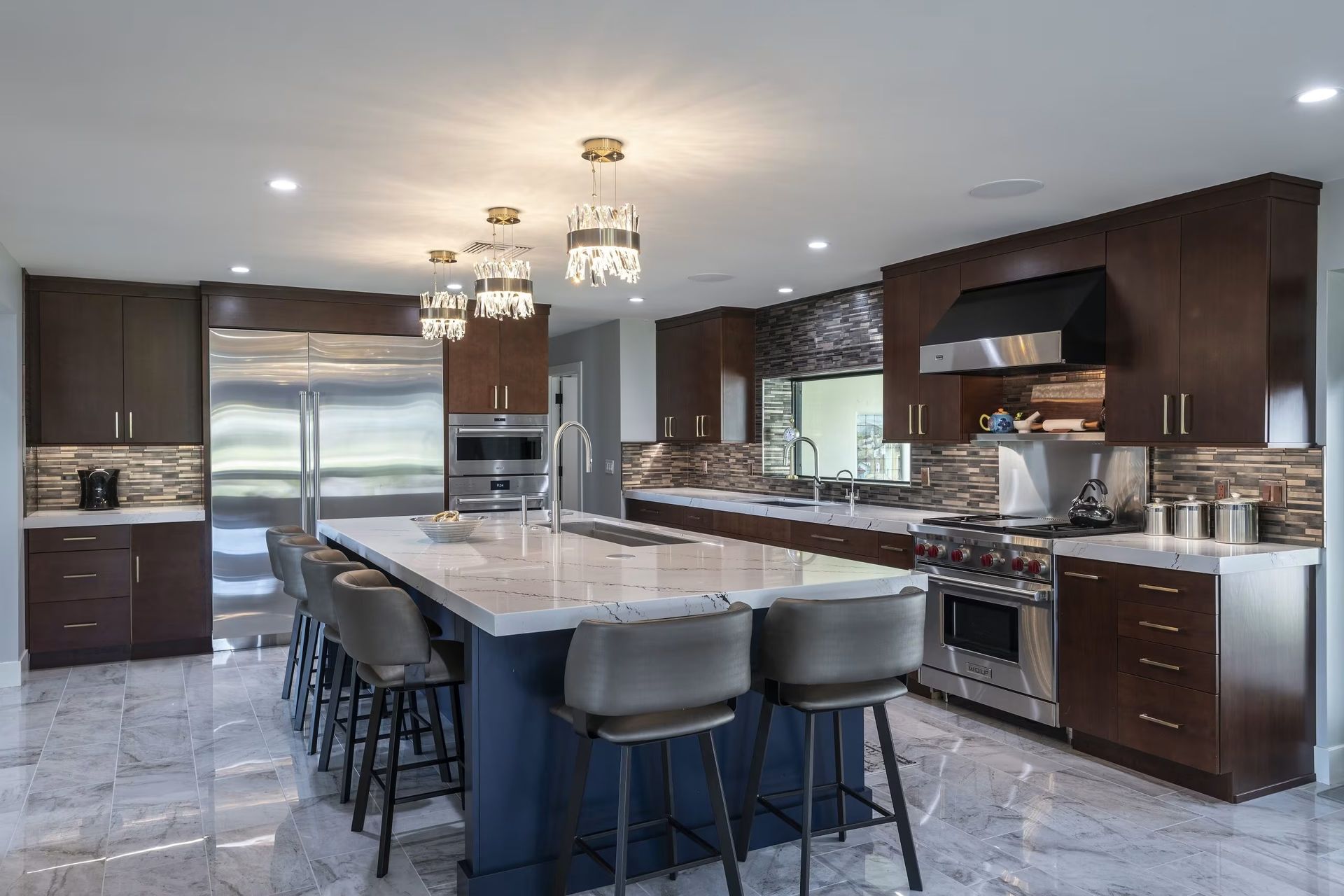 Modern kitchen with large island, dark wood cabinets, stainless appliances, and marble floors