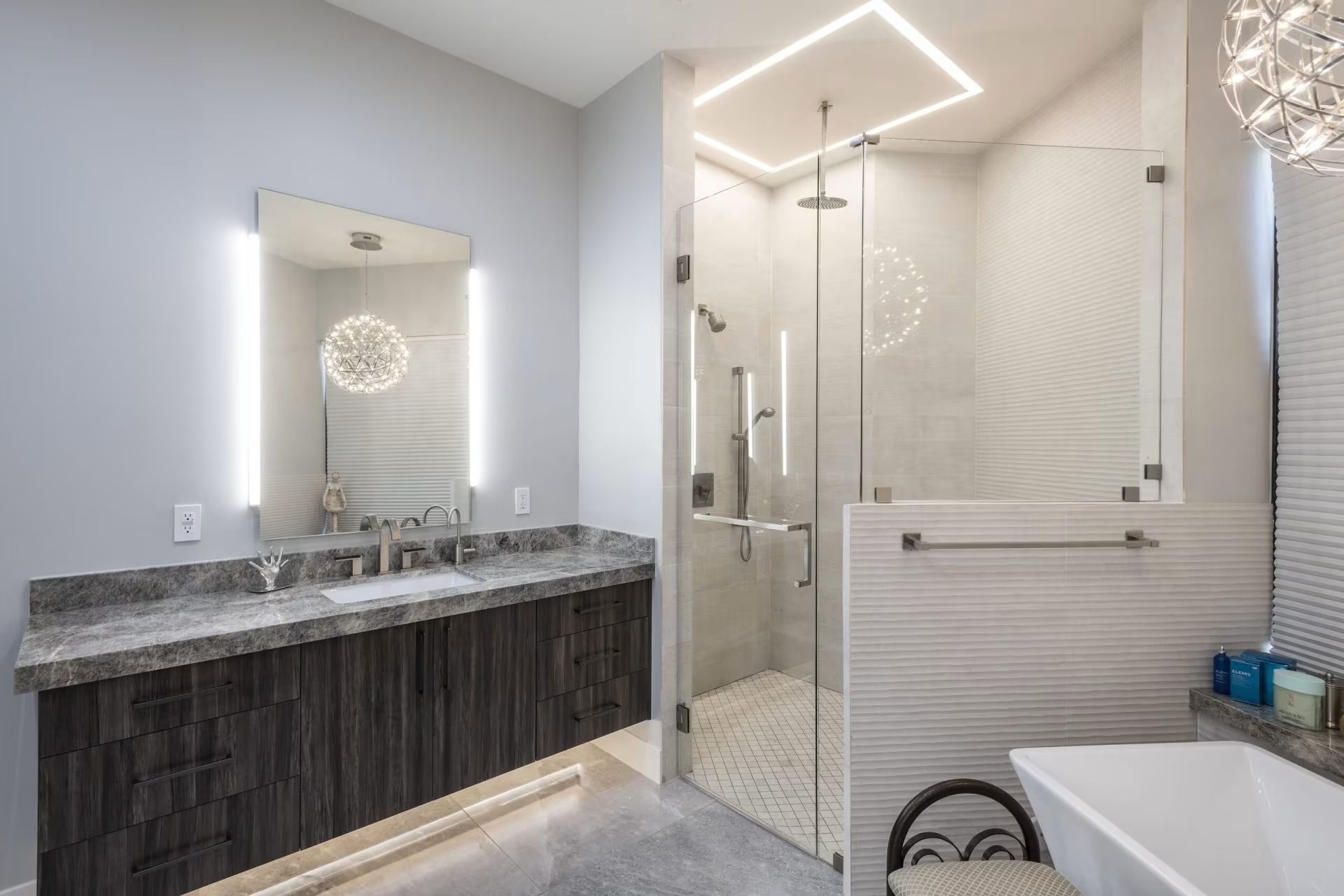 Modern bathroom with double vanity, large mirror, glass shower, and white tile walls