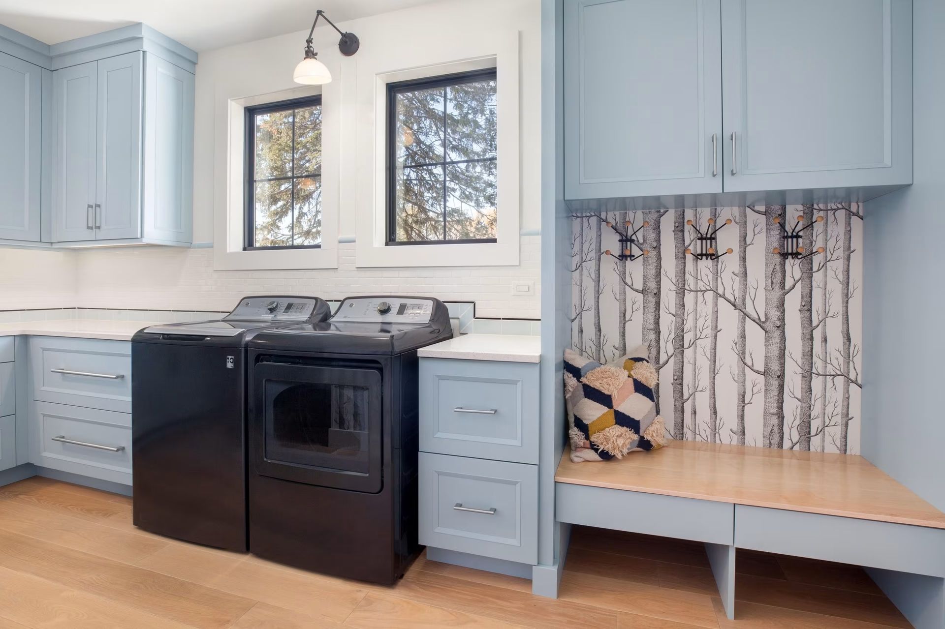 Bright kitchen with black stove, light blue cabinets, and a small built-in bench nook by the window.