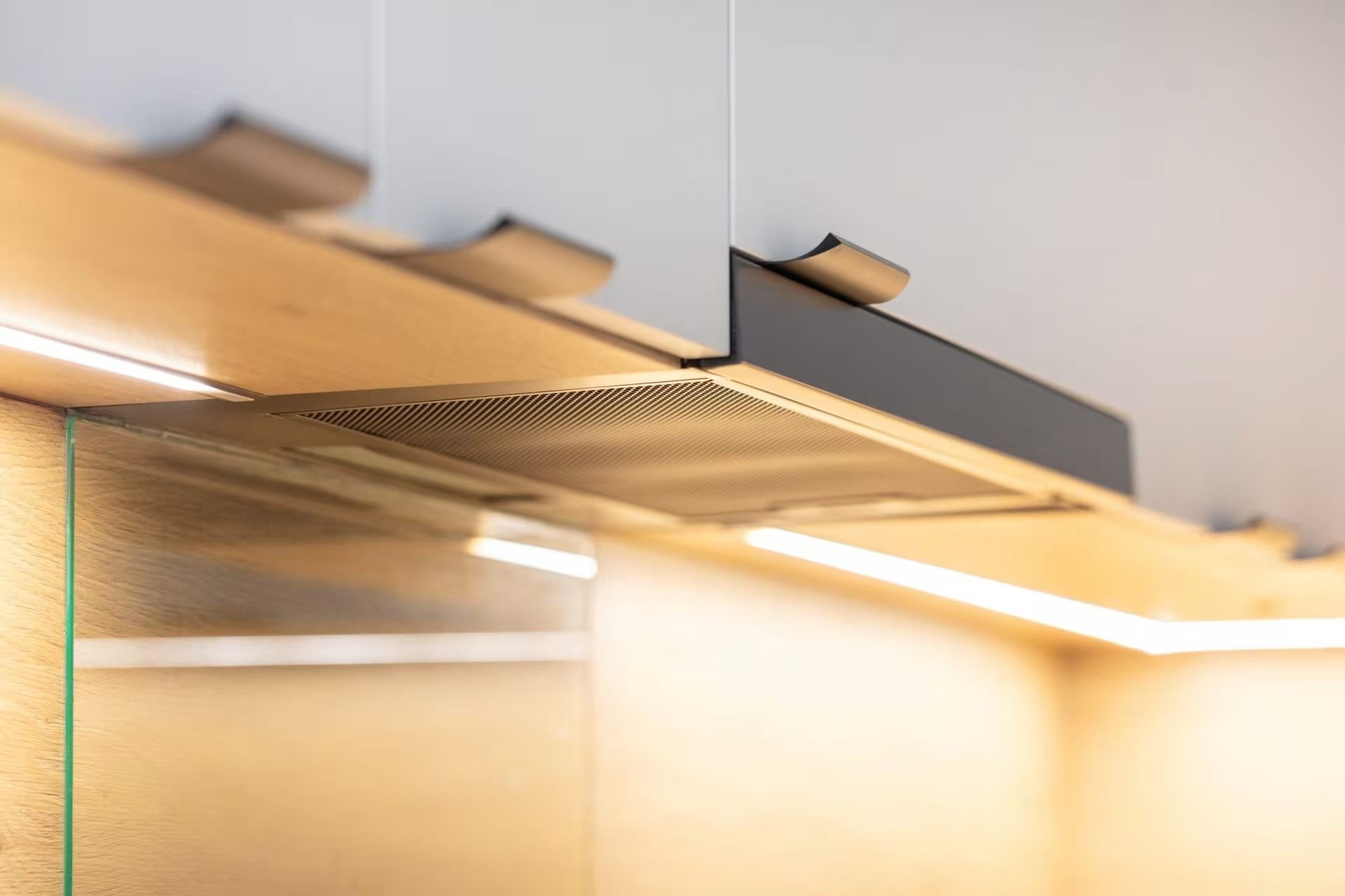 Close-up of a modern kitchen cabinet with under-cabinet lighting and metal handles