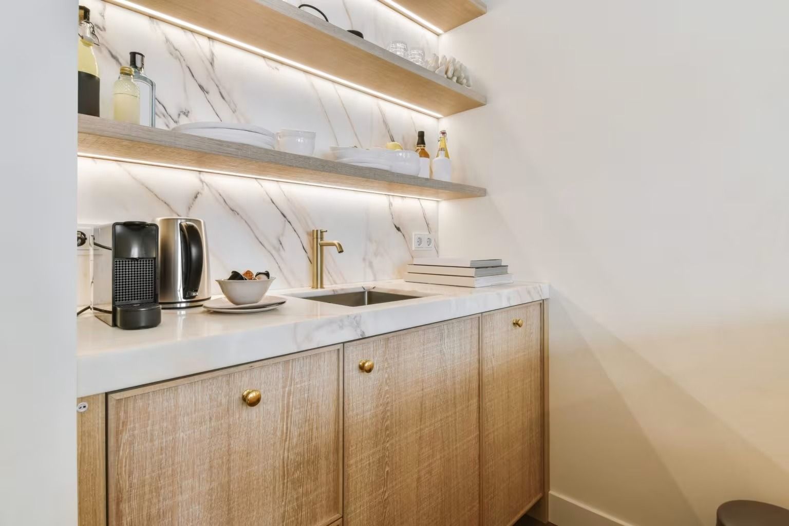Modern kitchen coffee and drink station with wood cabinets, open shelves, and countertop appliances