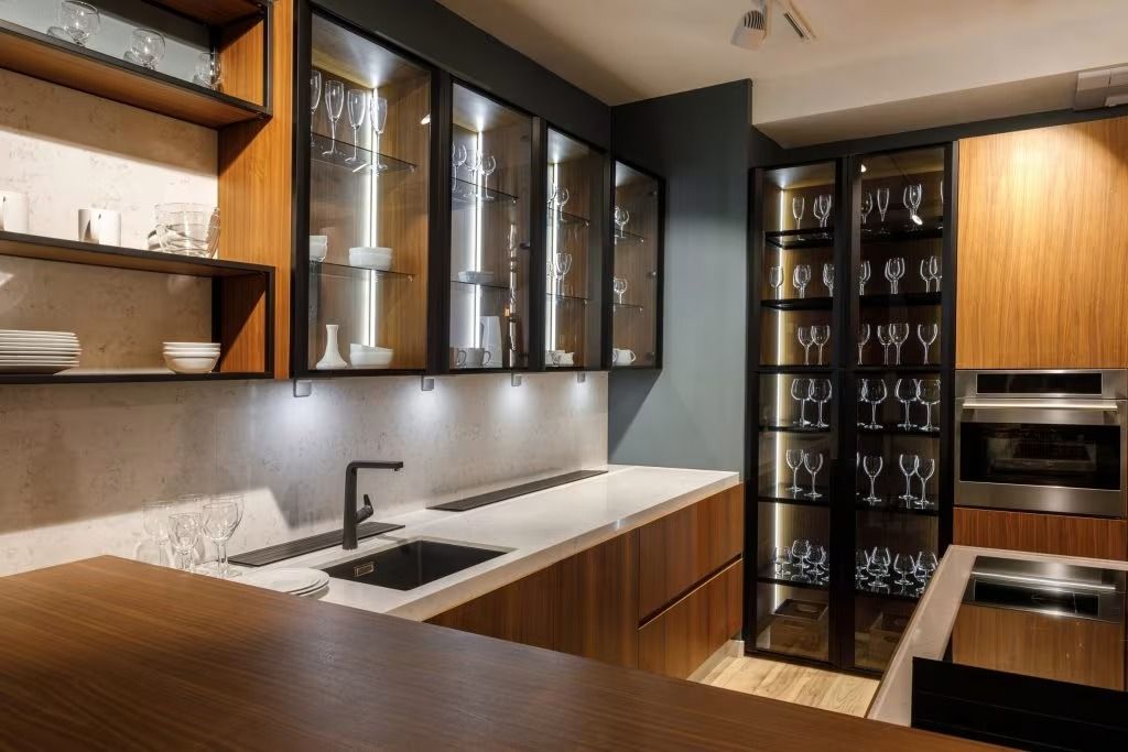 Modern kitchen with dark glass cabinets, white countertops, and built-in appliances