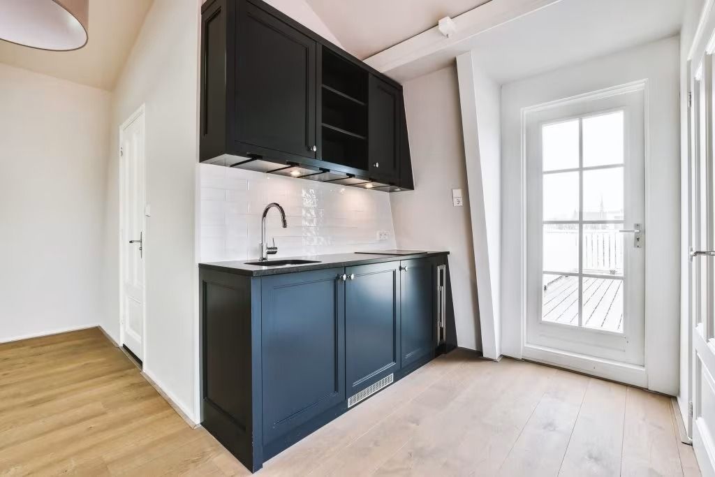 Small kitchen nook with dark cabinets, white walls, and a glass-paneled door.