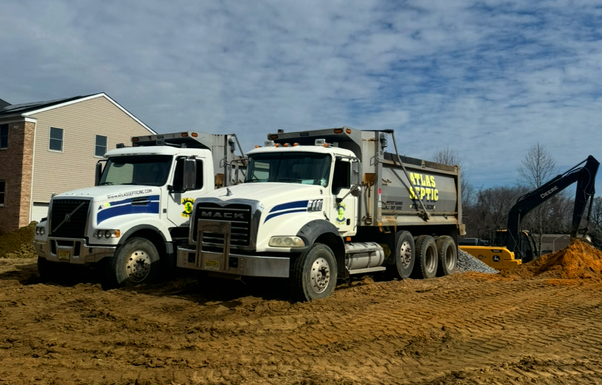 Two dump trucks and an excavator on a construction site.
