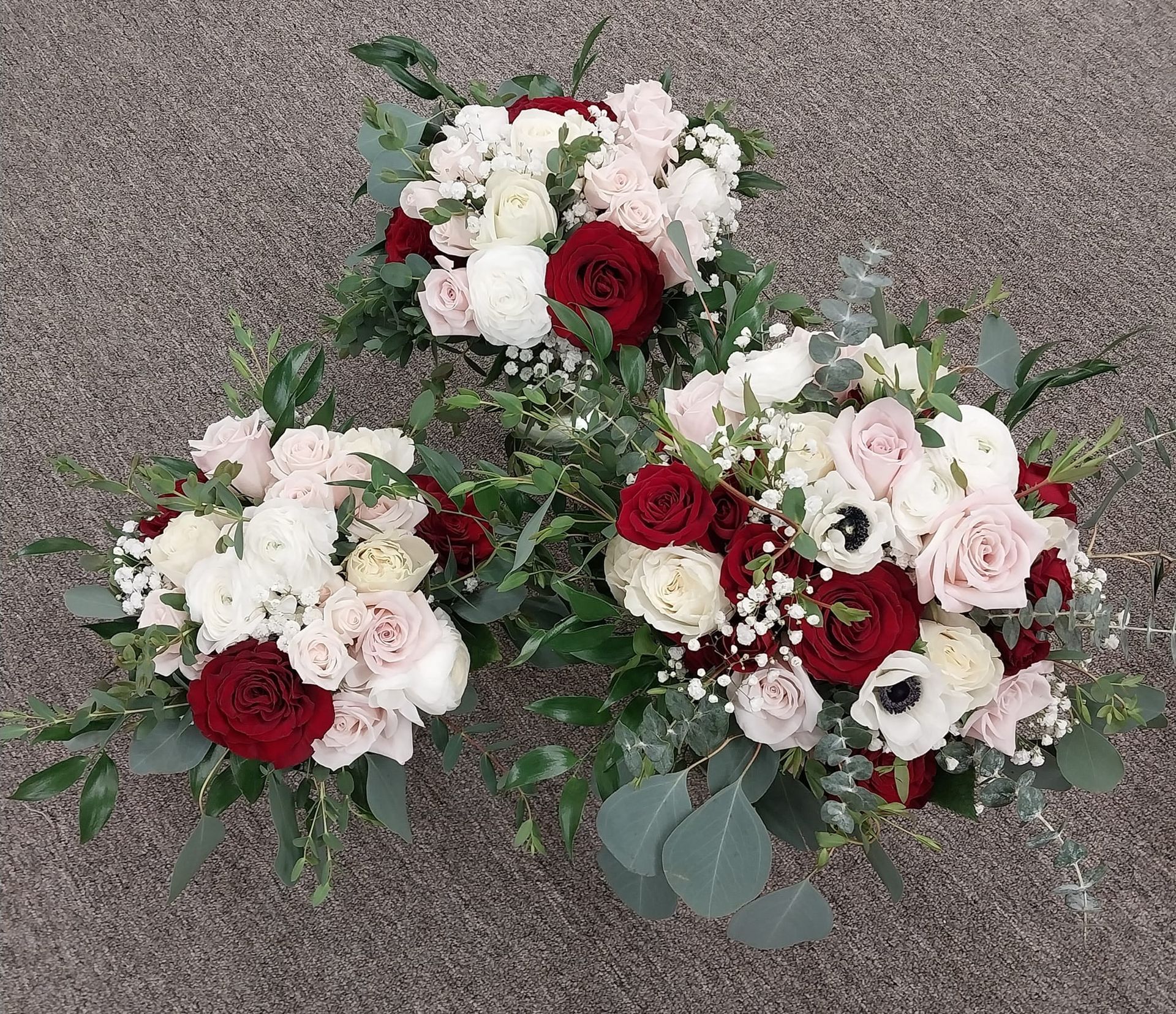 Three bouquets of red, white, and pink flowers.