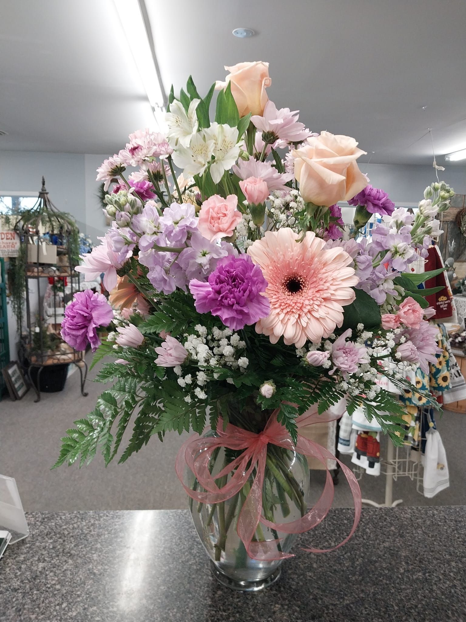 A vase filled with pink and purple flowers is sitting on a counter.