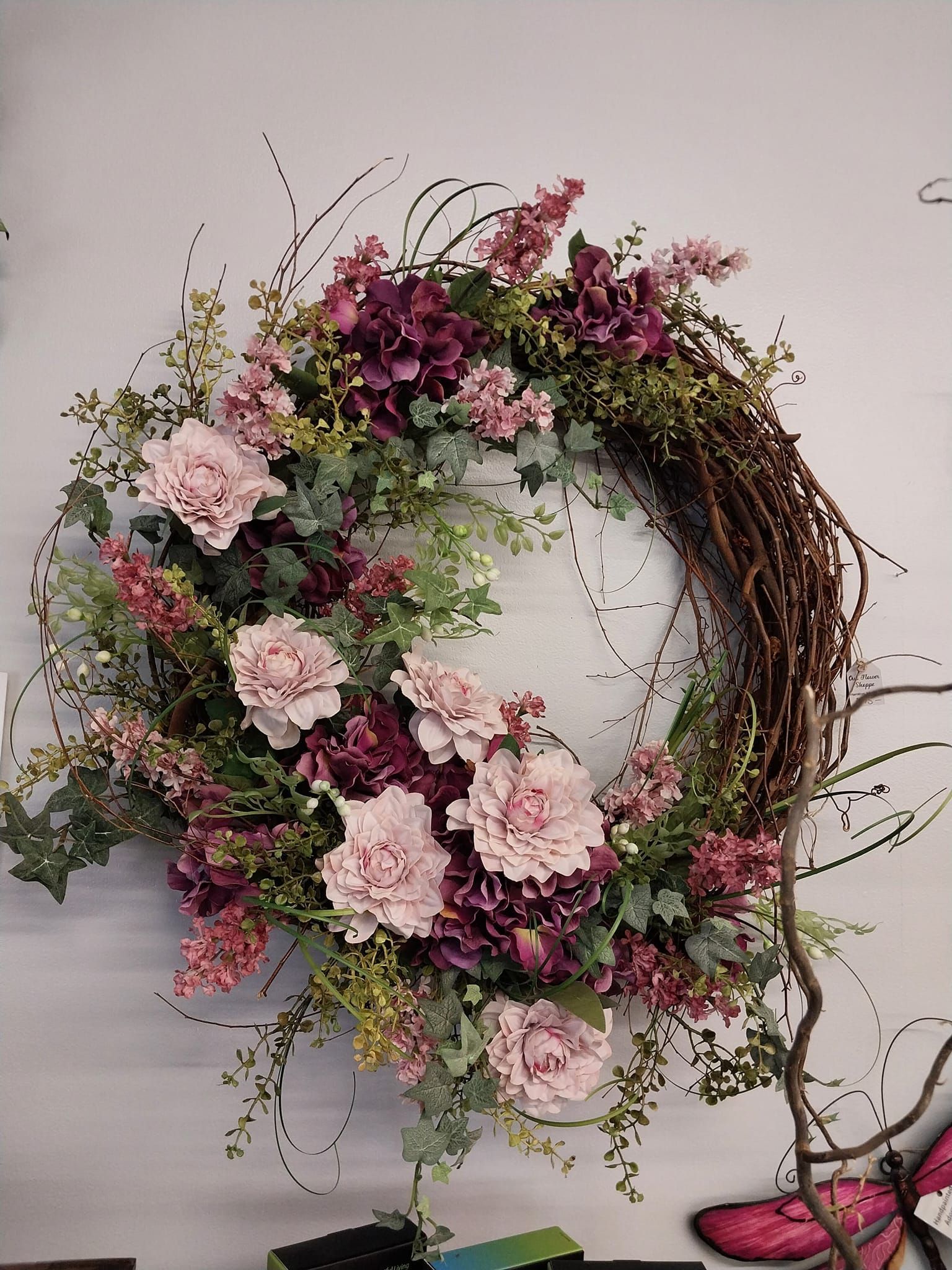 A wreath with pink and purple flowers is hanging on a wall.