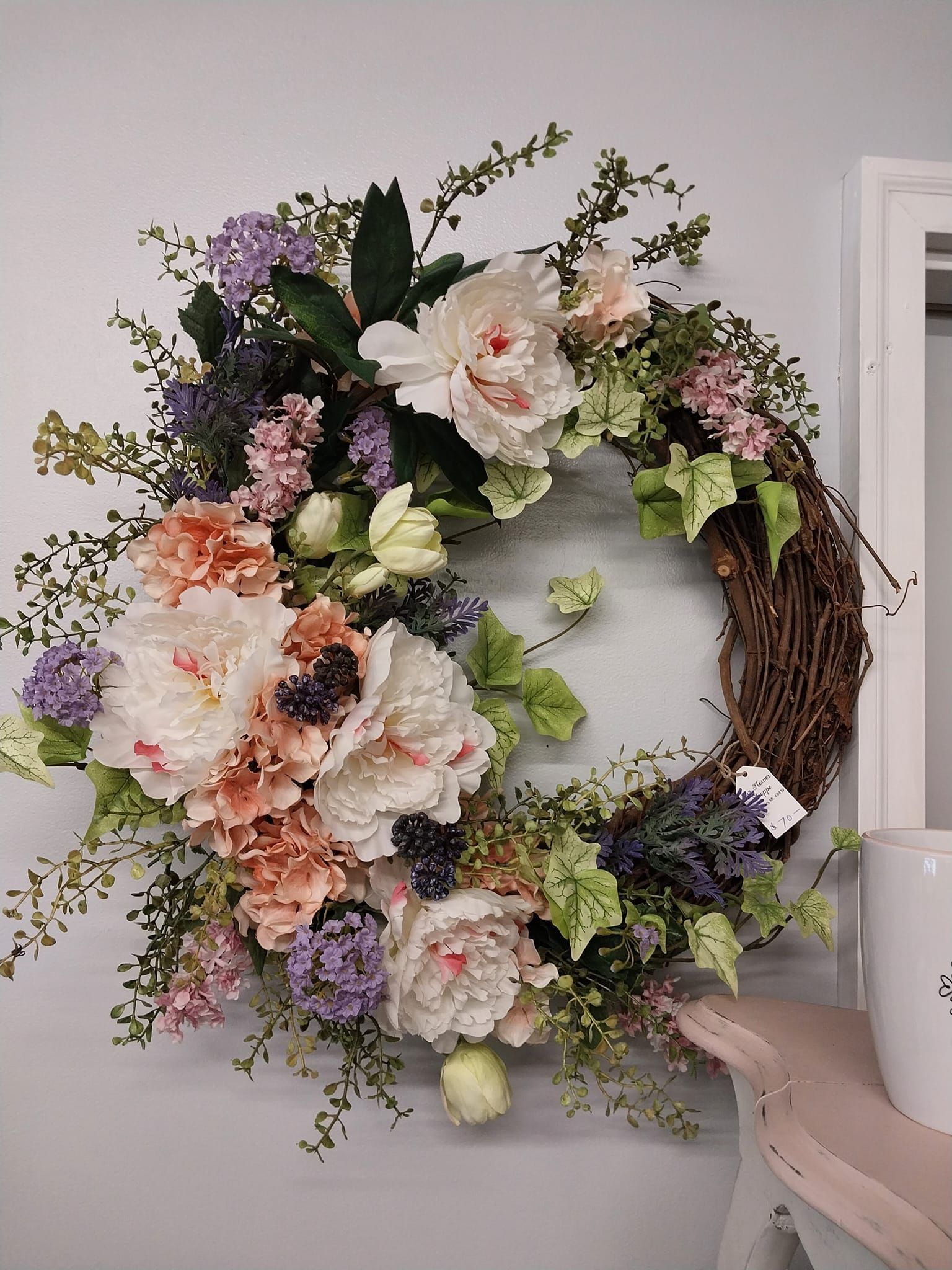 A wreath of flowers is hanging on a white wall.