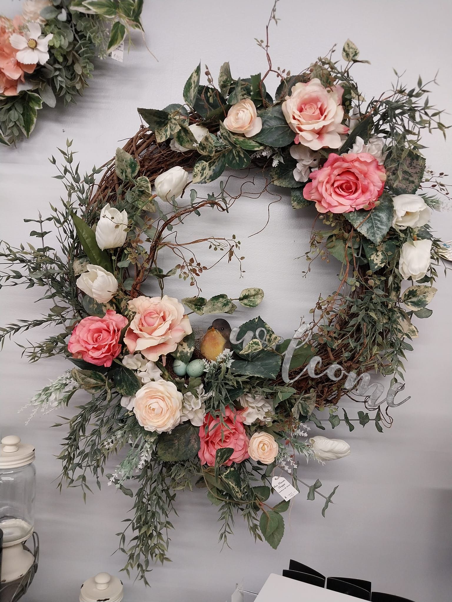 A wreath of pink and white flowers is hanging on a wall.