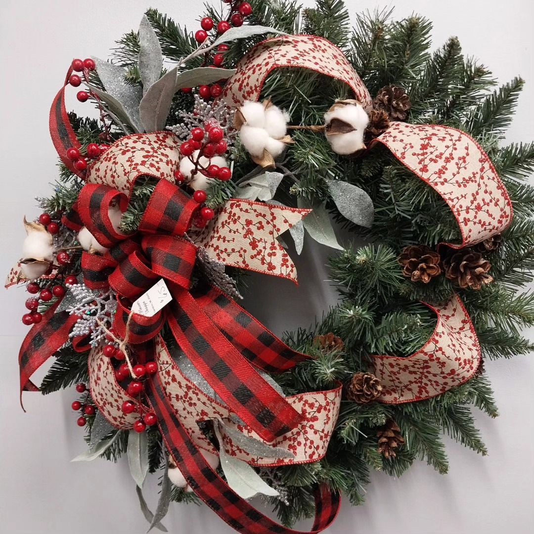 A Christmas wreath with red and black ribbons and berries.