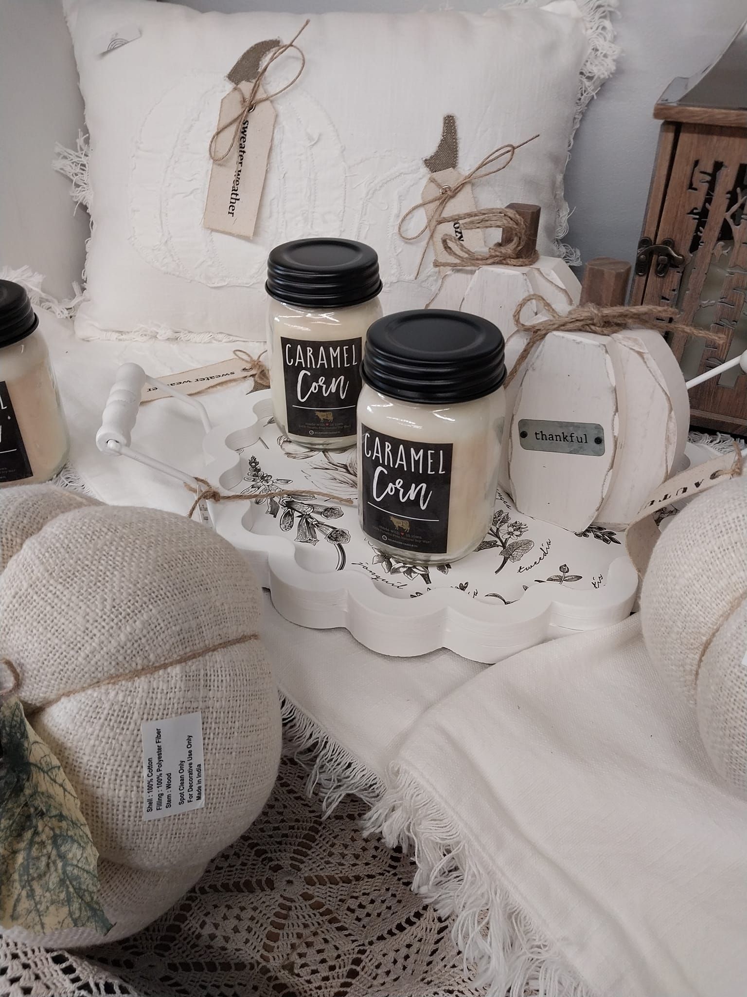 Three jars of candles are sitting on a table next to a pillow.