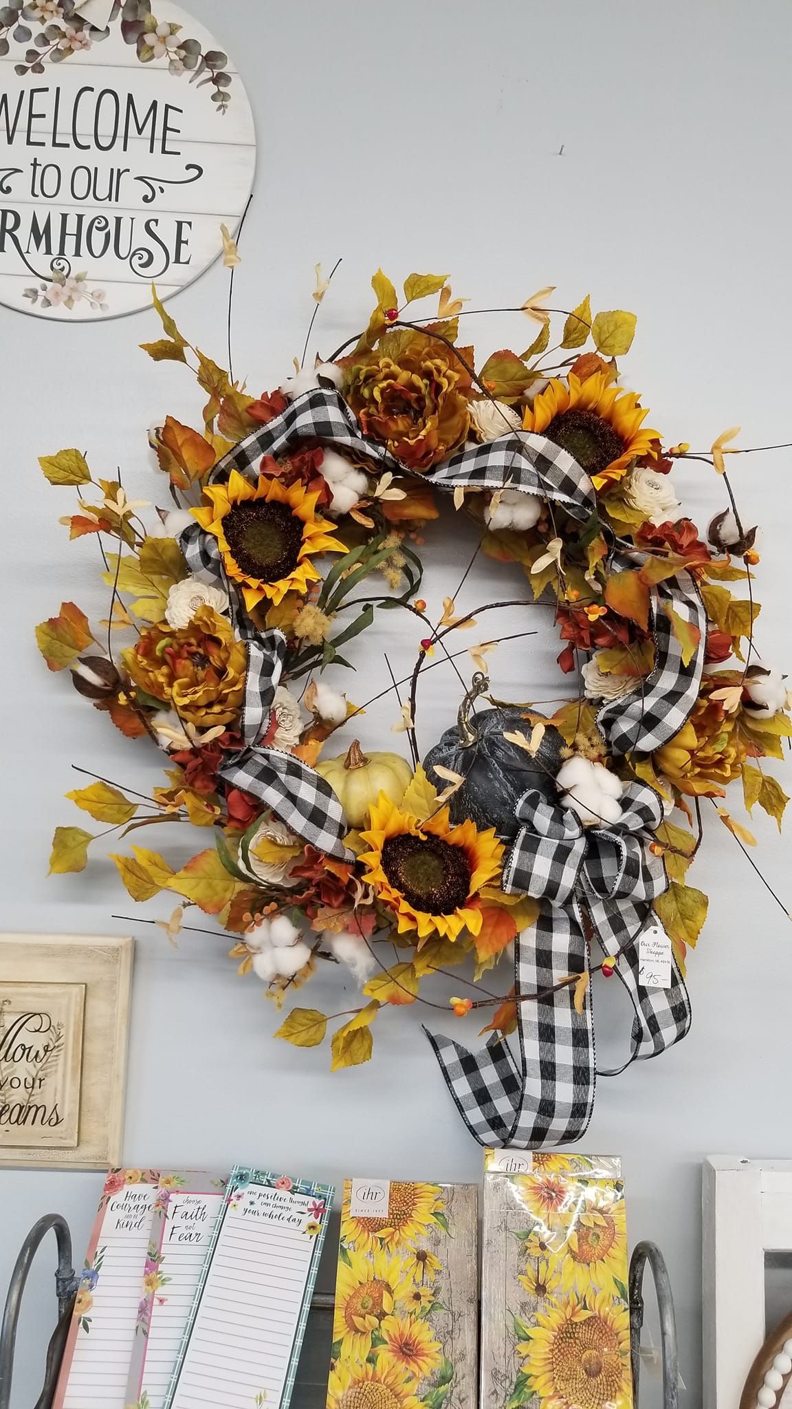 A wreath with sunflowers and leaves is hanging on a wall.