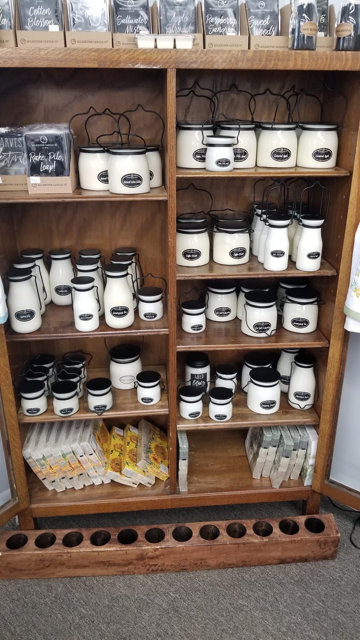 A wooden shelf filled with lots of jars and candles.