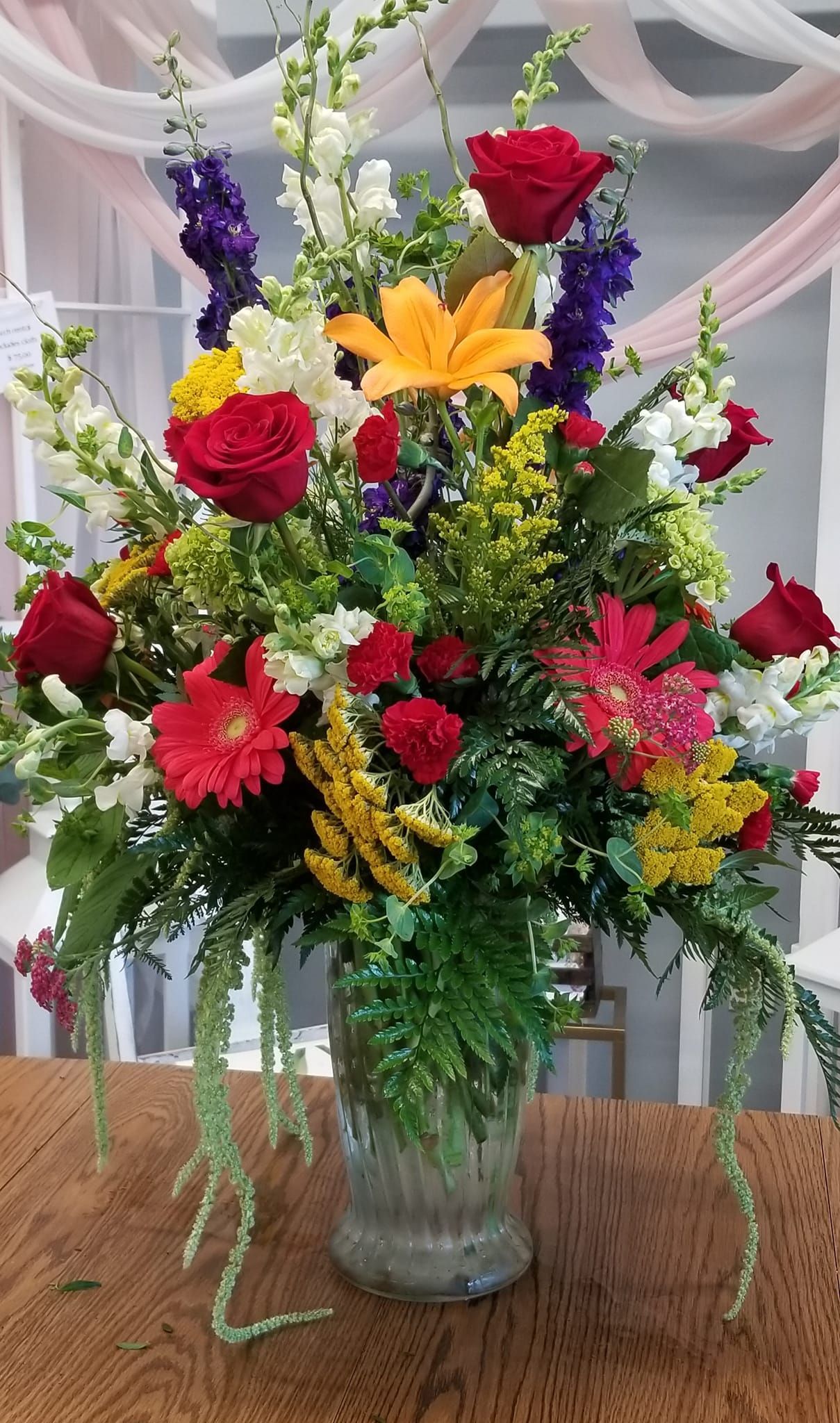 A vase filled with colorful flowers is sitting on a wooden table.