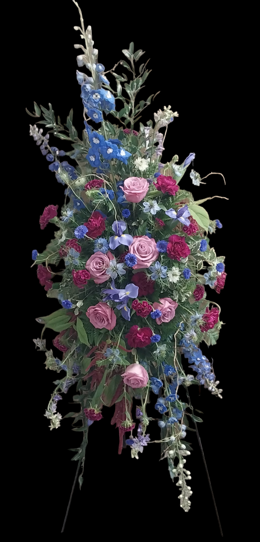 A large bouquet of pink and blue flowers on a stand on a black background.