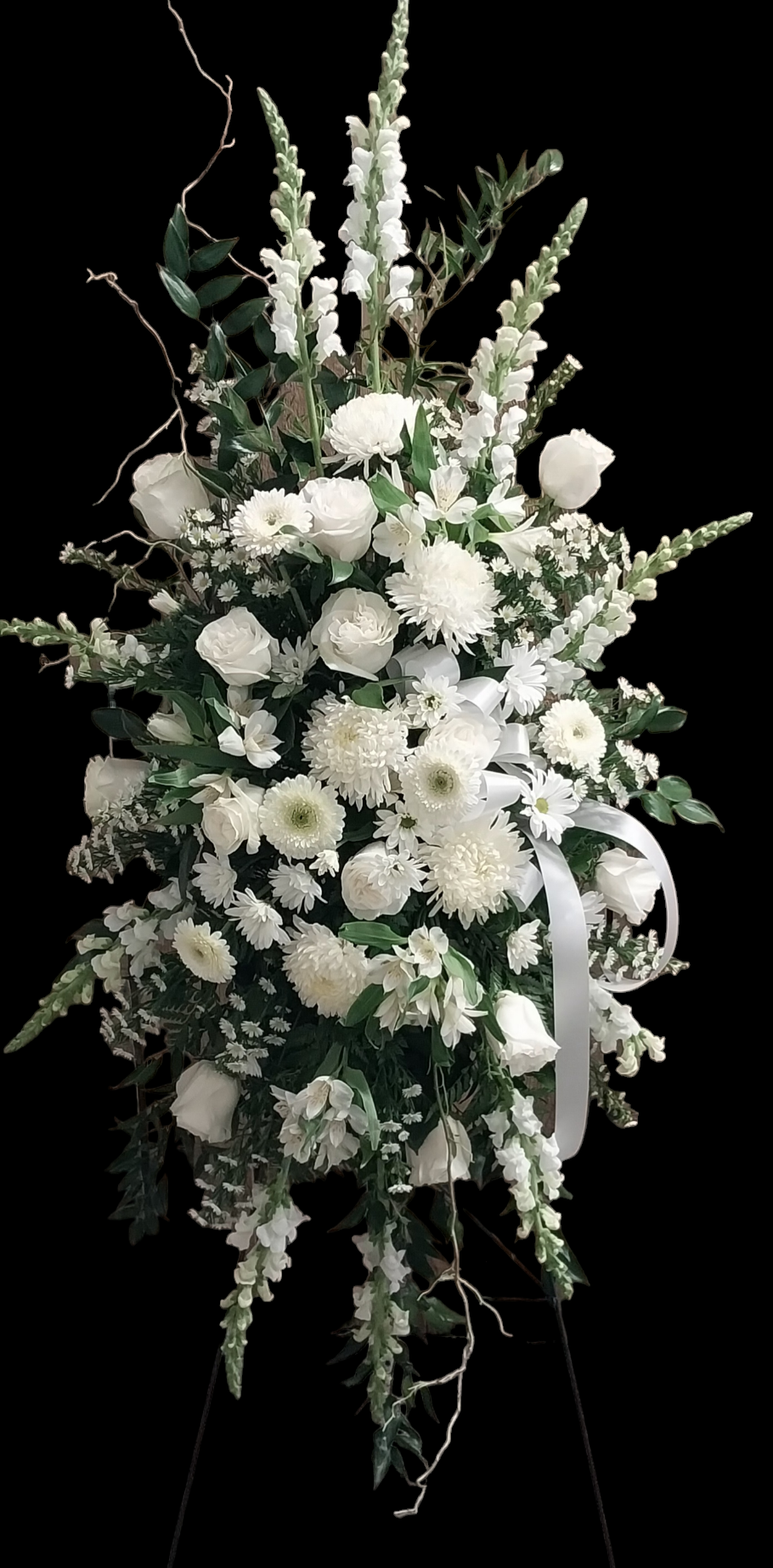 A display of white flowers on a stand on a black background.