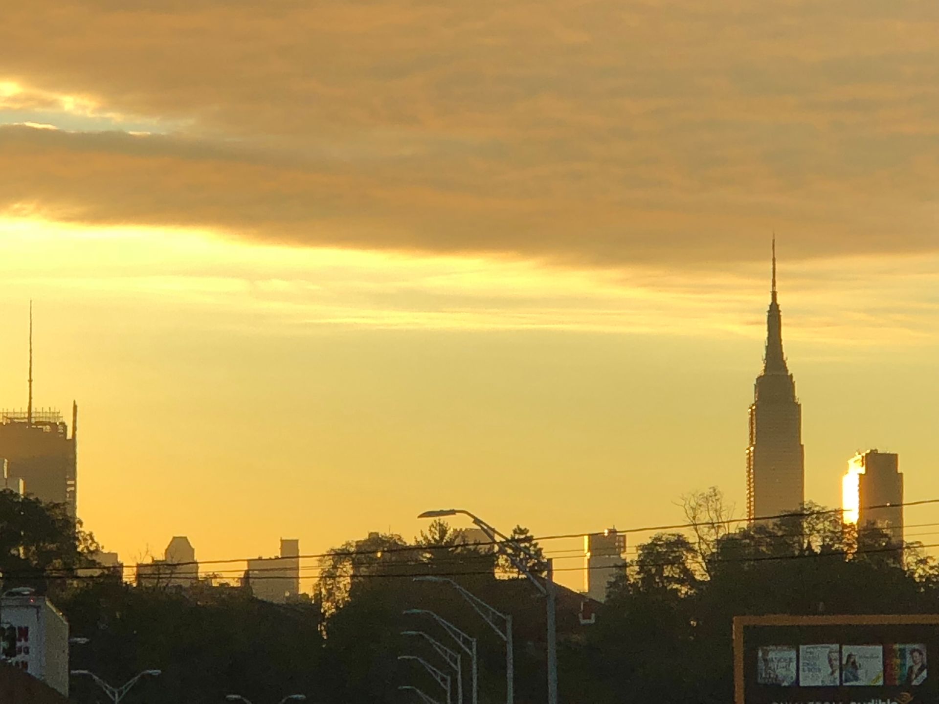 Golden sunrise over the New York City skyline, with the Empire State Building prominent.