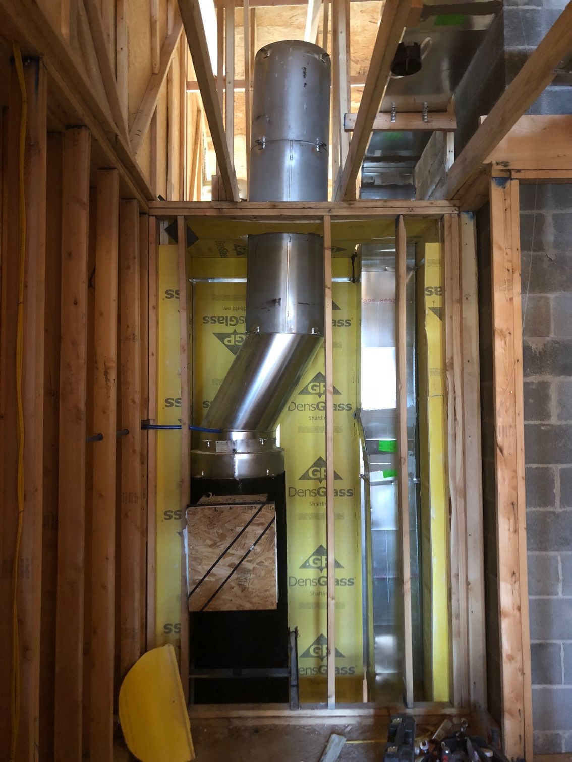 Framed walls with metal chimney and ductwork; yellow insulation visible.