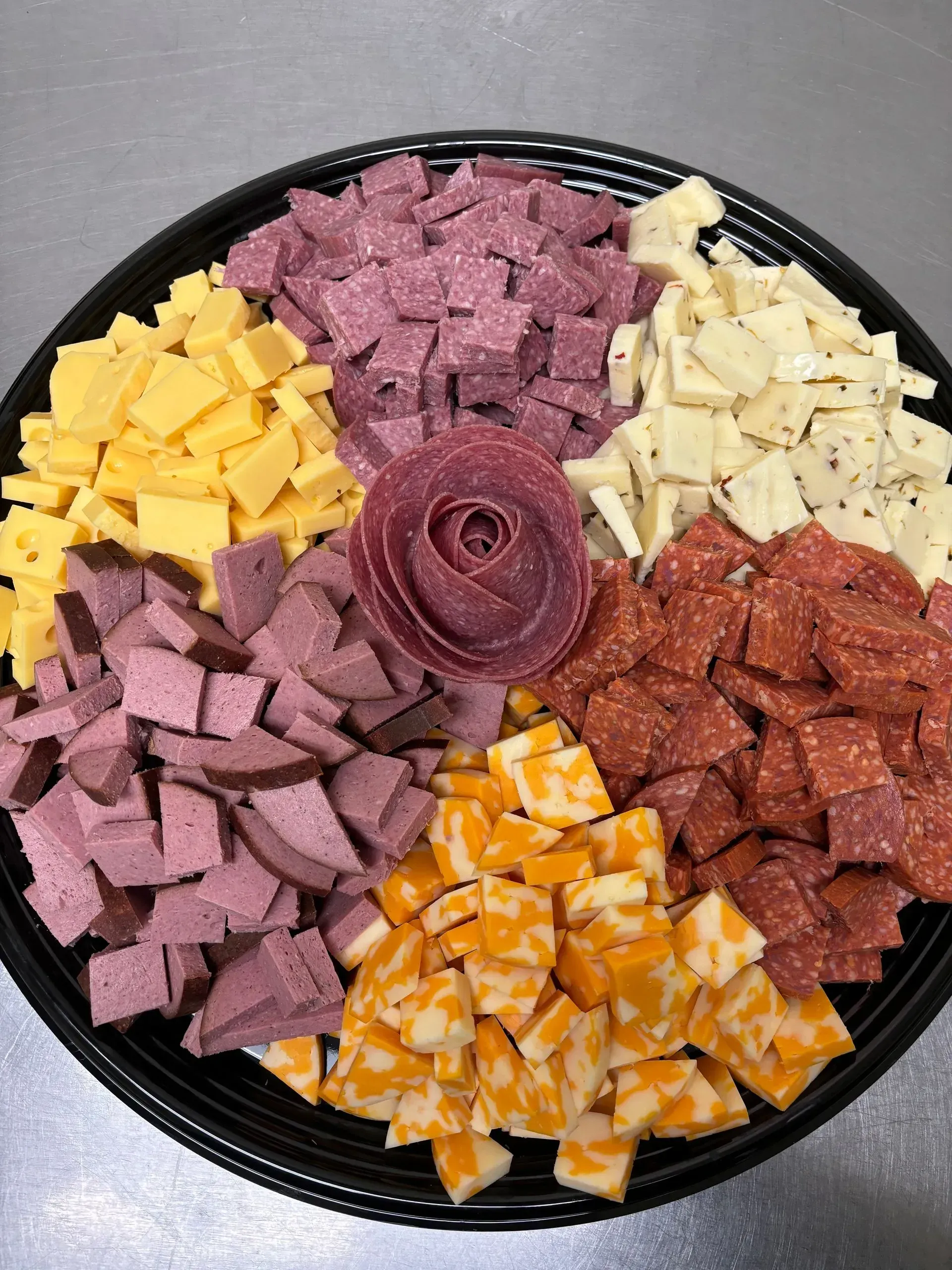 Charcuterie platter with cubed cheeses and meats, including a salami rose centerpiece.