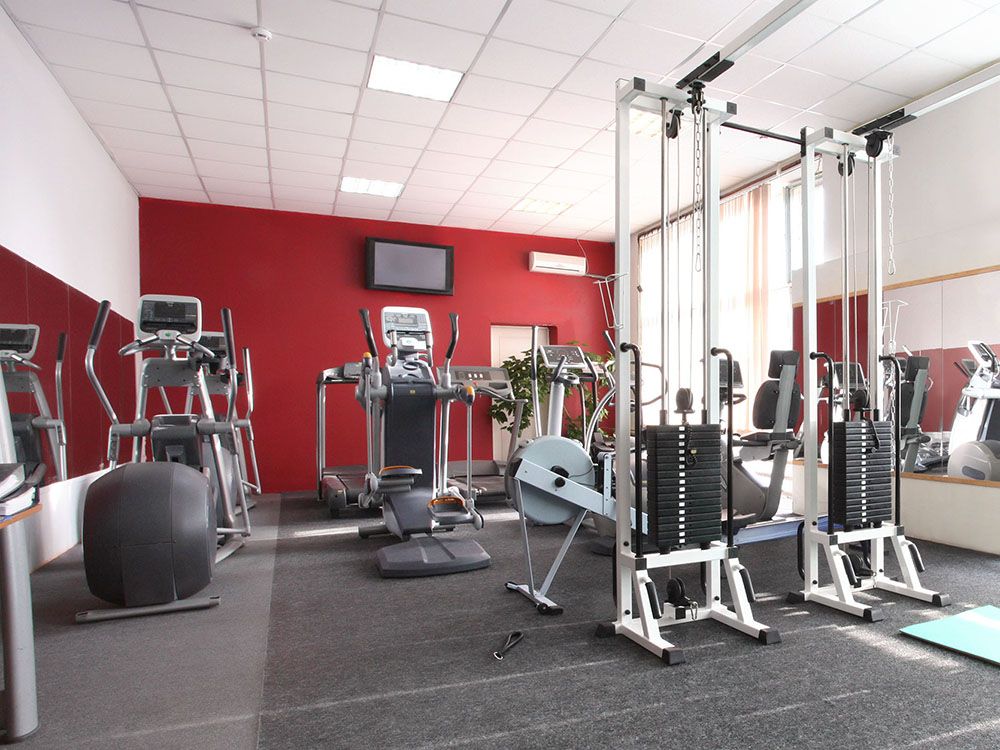 A gym with a lot of equipment and a red wall