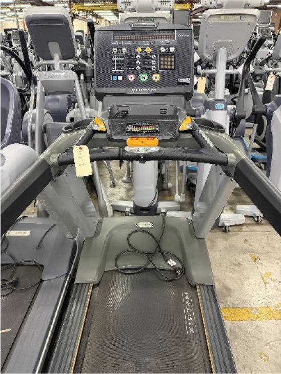 Treadmill cardio machine in a gym, with control panel and handlebars in view.