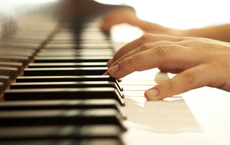 A close up photo of a person's hands playing piano