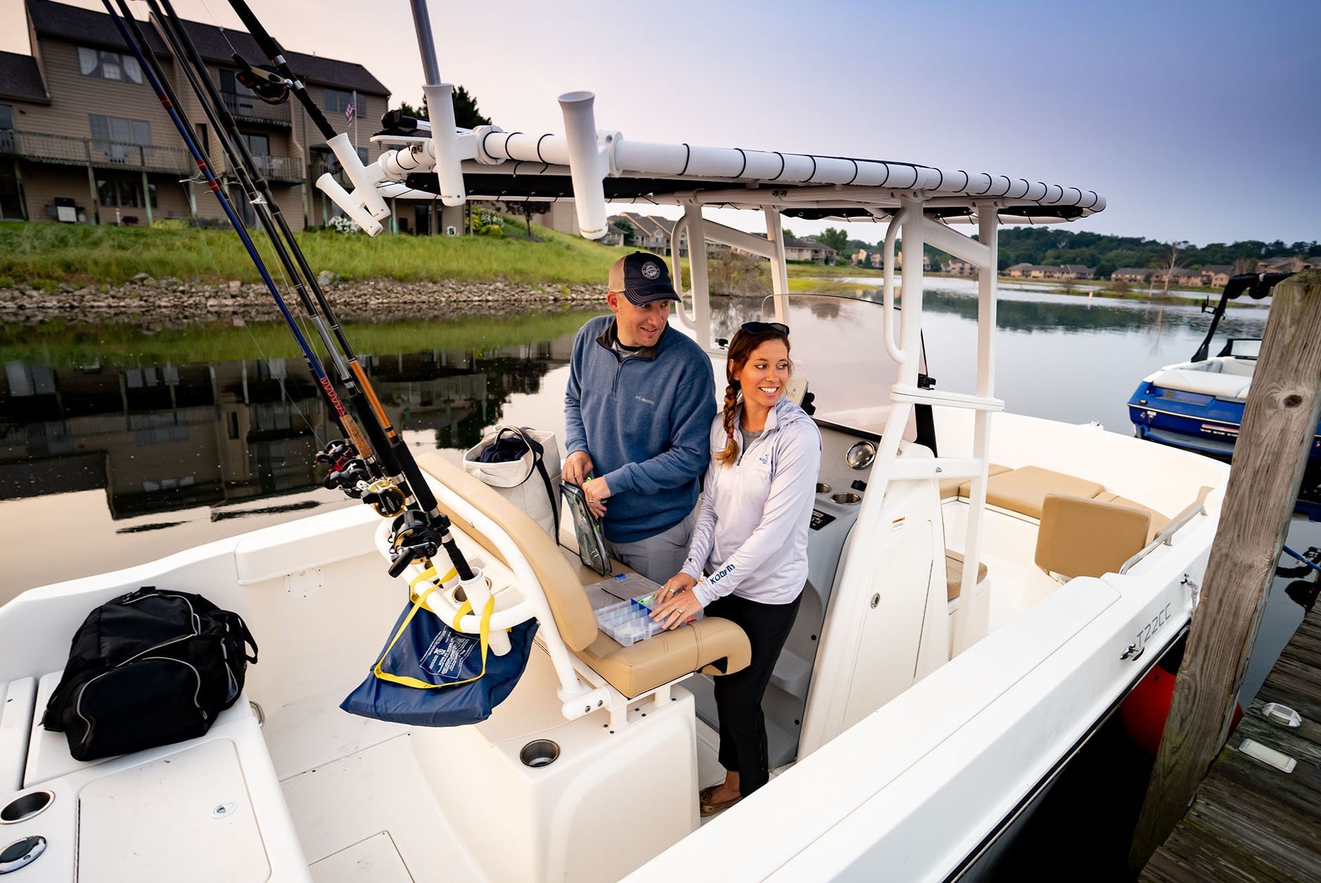 A man and woman on a white fishing boat at a dock. They are smiling.