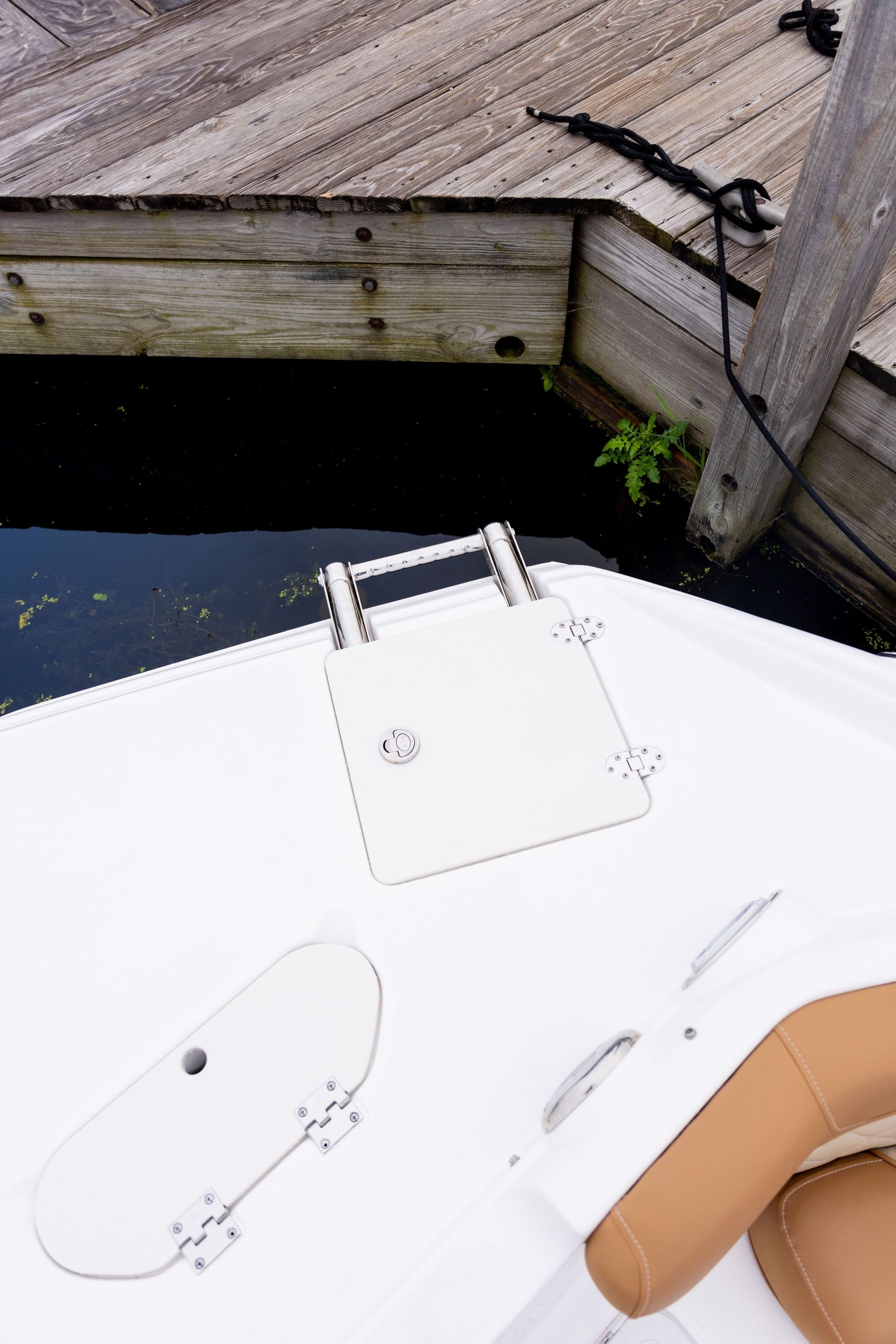 A white boat is docked next to a wooden dock.