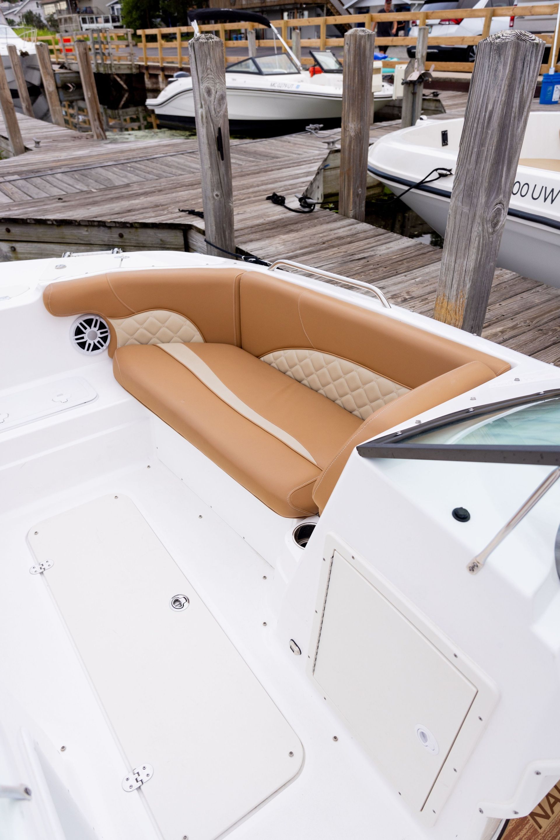 A white boat with a brown seat is docked at a dock.