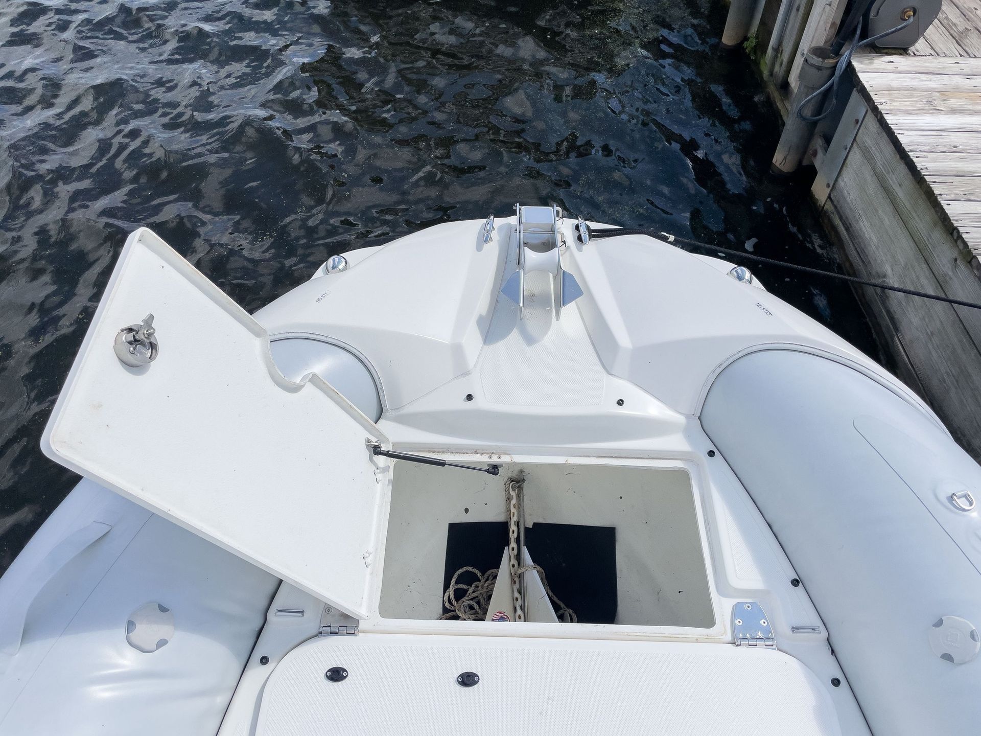 A white boat is docked at a dock with the door open