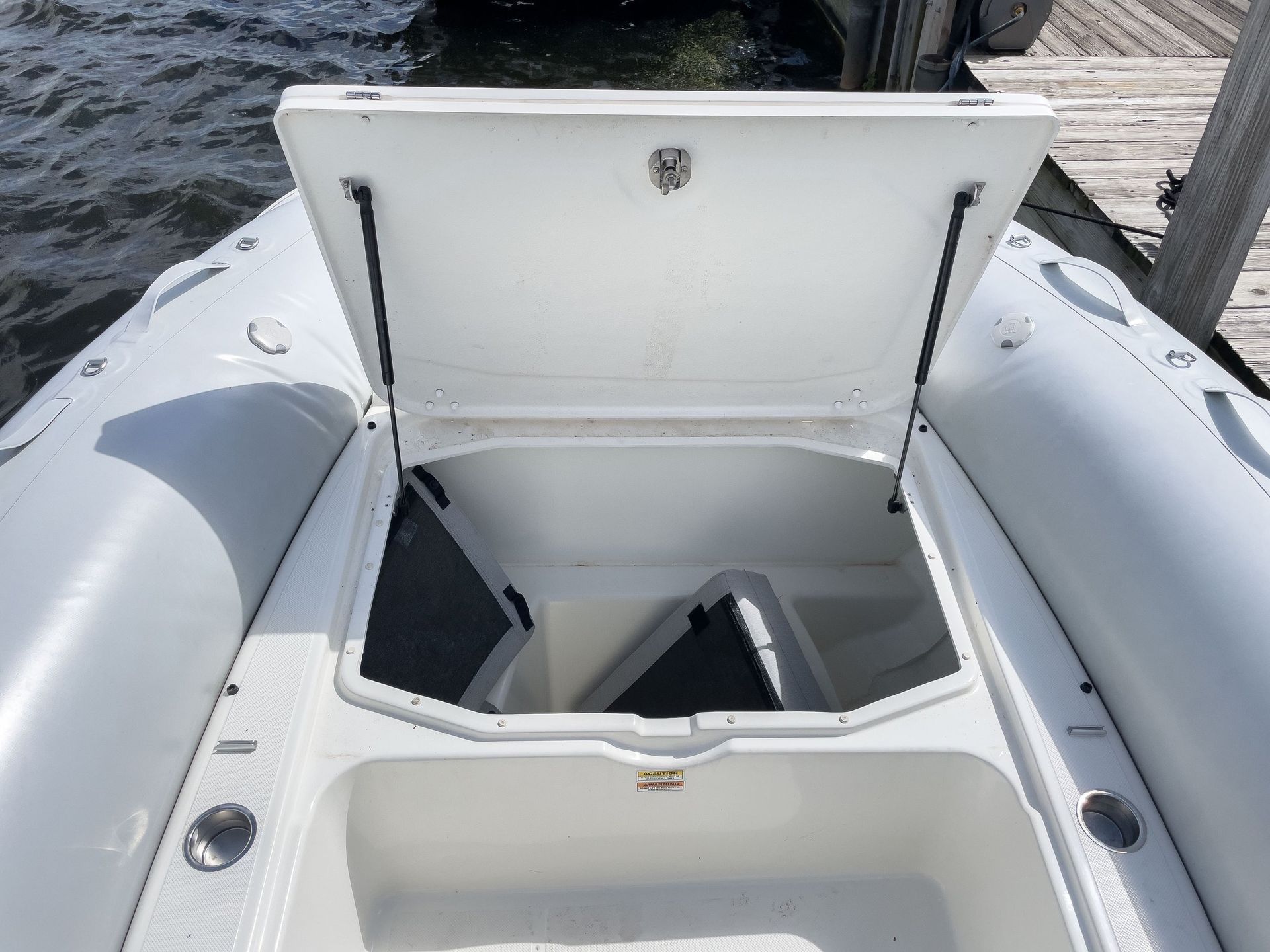 A white boat with the lid open is docked at a dock.