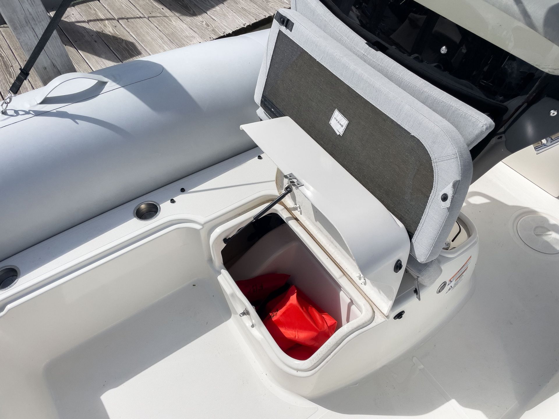 A boat with the back seat open and a red bag in it