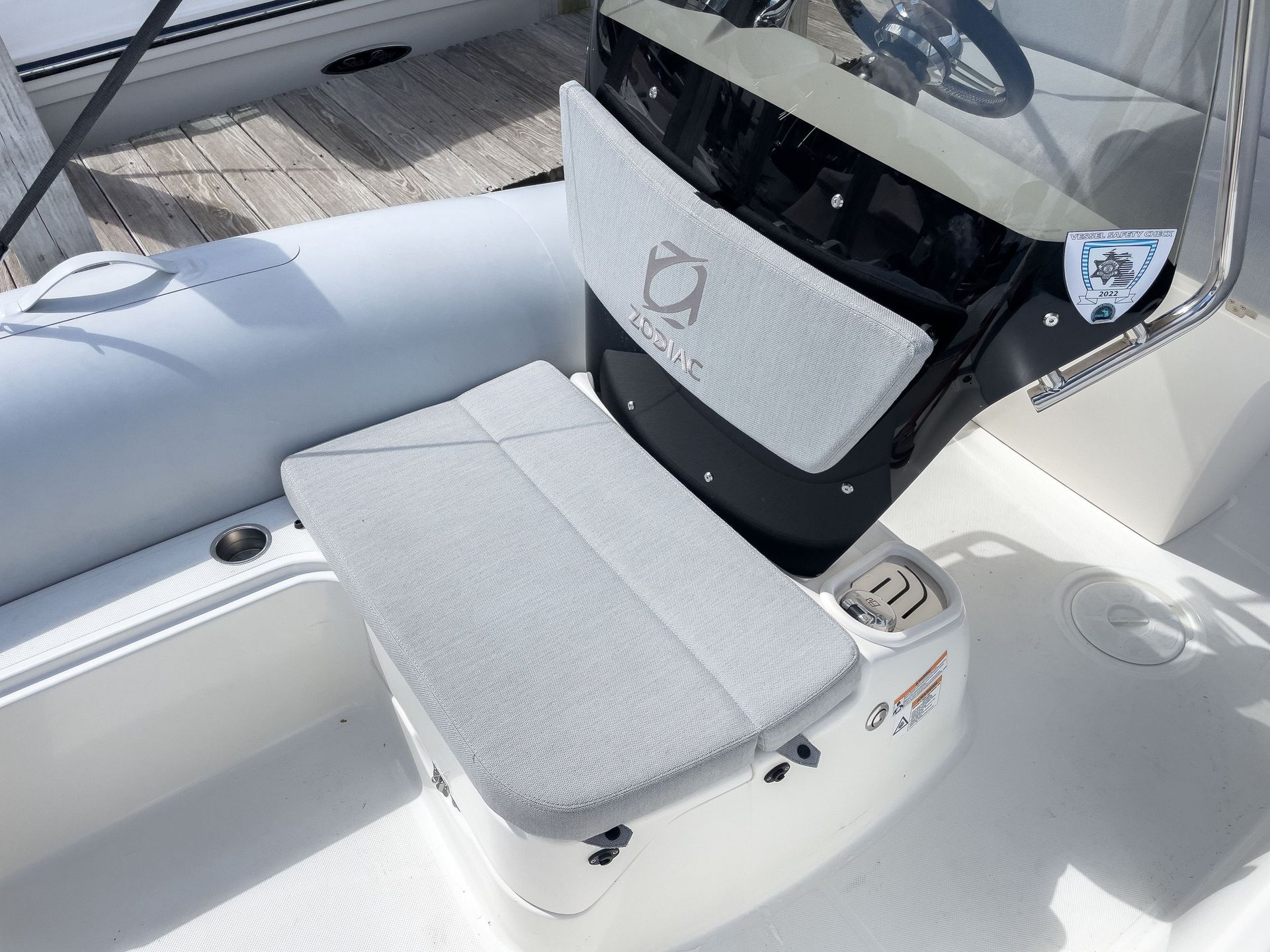 A white boat with a seat and steering wheel