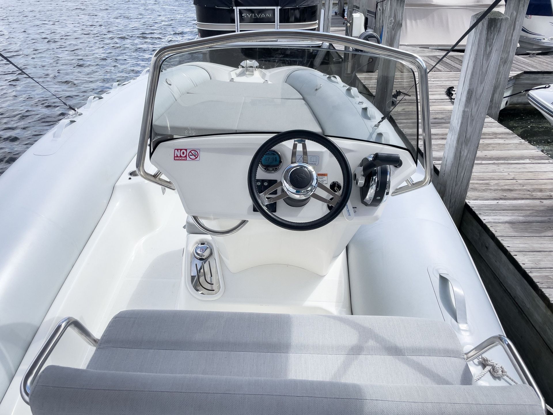 A white boat with a steering wheel is docked at a dock.
