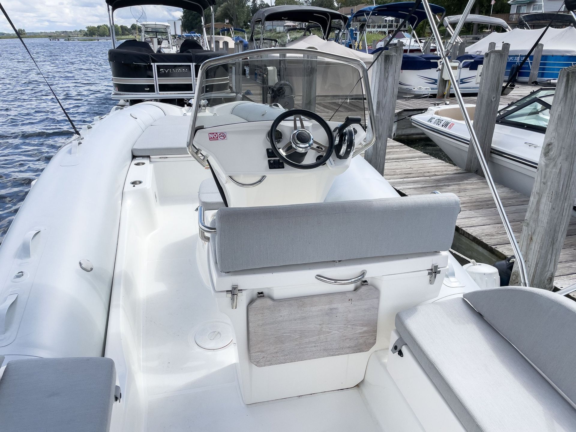 A white boat with a steering wheel is docked at a dock